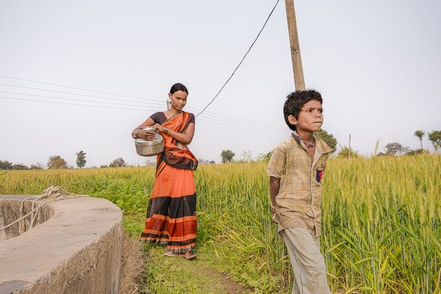 A farming couple standing together at the edge of their field