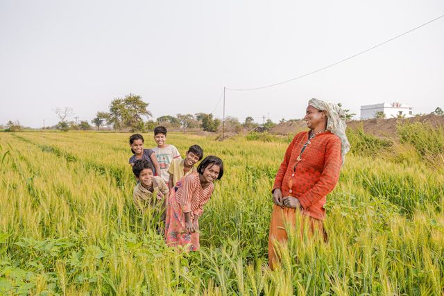 A farming family standing together in a field of tall crops