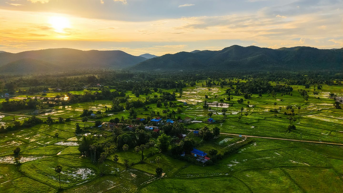 Aerial view of a rural village surrounded by green fields at sunset